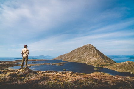 Outdoor guy standing at plateau looking towards mountain top landscape trekking travel summer concept. Success and freedom.の写真素材