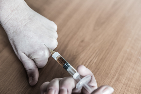 Person sets a syringe needle with heroinの写真素材