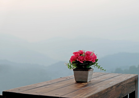 flower in vase on wooden table and background moutainの写真素材