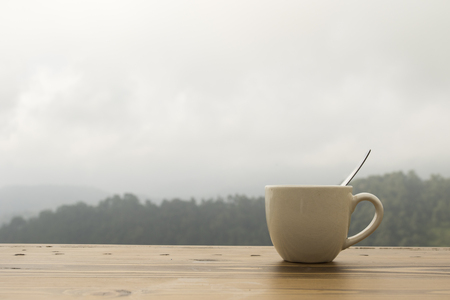 coffee cup on wooden table with natural moutain backgroundの写真素材