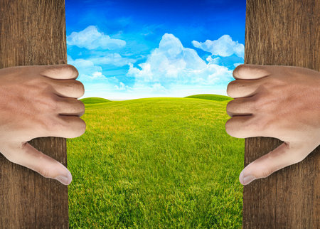 Hands open door into green fieldの写真素材