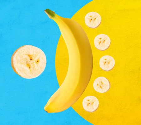Fresh yellow banana with banana slices isolated on blue and yellow backgroundの写真素材
