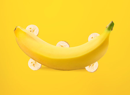 Ripe banana with banana slices isolated on yellow backgroundの写真素材