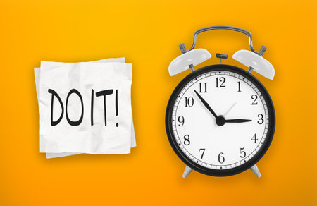 Black and white alarm clock and paper reminder, do it. Time management, priorities, efficiency, control and goals conceptの写真素材