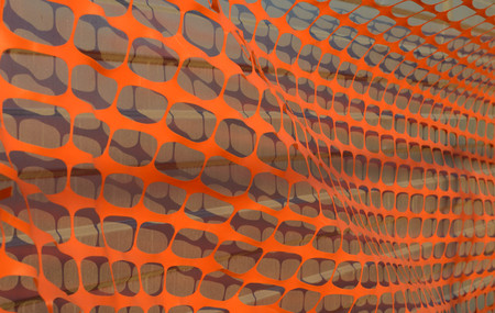 Iron fence covered with orange perforated mesh. The size lit sunの写真素材