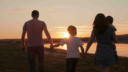 happy family at sunset silhouette of the waterの写真素材