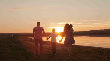 happy family at sunset silhouette of the waterの写真素材