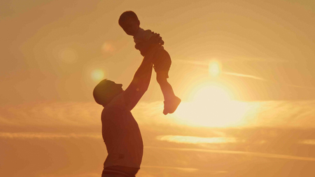 father and son silhouettes play at sunset beach. Happy familyの写真素材