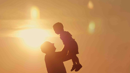 father and son silhouettes play at sunset beach. Happy familyの写真素材