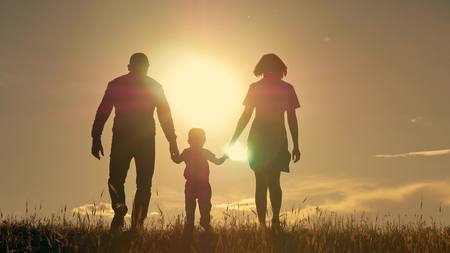 Happy young family with children running around the field, silhouette at sunsetの写真素材