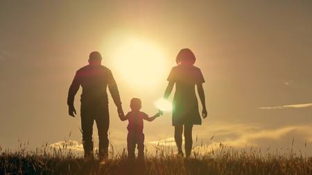 Happy young family with children running around the field, silhouette at sunsetの写真素材