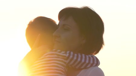 Happy family mom and son in a wheat field at sunsetの写真素材