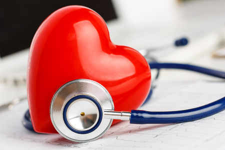 Medical stethoscope and red toy heart lying on cardiogram chart closeup. Medical help, prophylaxis, disease prevention or insurance concept. Cardiology care,health, protection and prevention