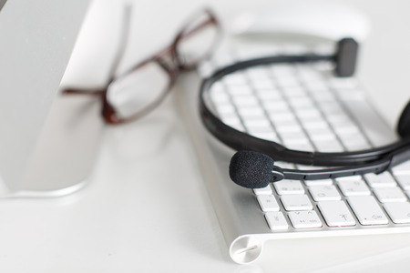 Call center service operator's empty working place. Headset, glasses, keyboard and monitor at...