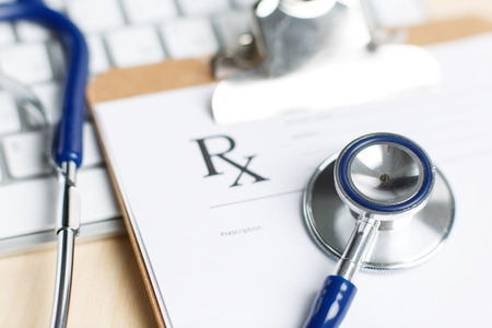 Prescription form clipped to pad lying on table with keyboard and stethoscope. Medicine or pharmacy concept. Empty medical form ready to be usedの写真素材
