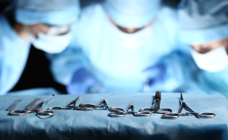 Surgical tools lying on table wile group of surgeons at background operating patient in surgical...