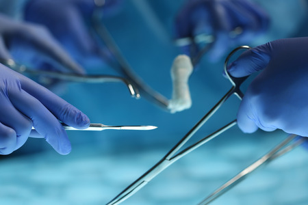 Surgeons hands holding surgical instrument while operating patient in surgical theatre. Resuscitation medicine team holding steel medical tools saving patient. Surgery and emergency conceptの写真素材