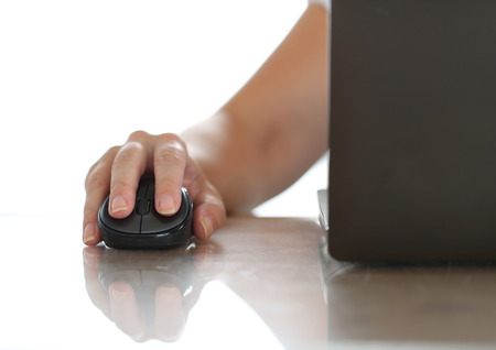 Female hand holding computer wireless mouse working with notebook pc. Working with computer, internet surfing, entertainment or business conceptの写真素材