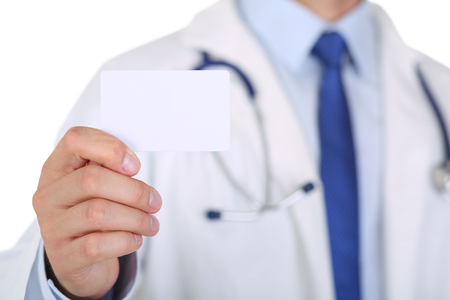 Male medicine doctor hand holding blank calling card. Physician showing white visiting card in camera closeup. Contact information exchange concept. Introducing gesture at formal meetingの写真素材