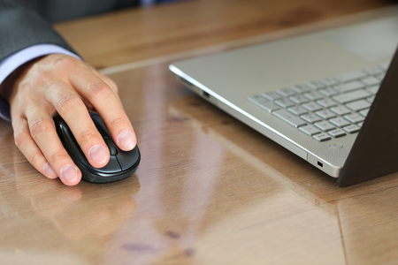 Hands of businessman in suit holding computer wireless mouse working with notebook pc. Working with...
