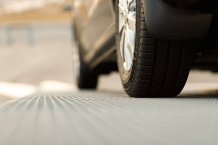 Dark automobile standing on steel floor view from below. Car parking problems, motor show or...