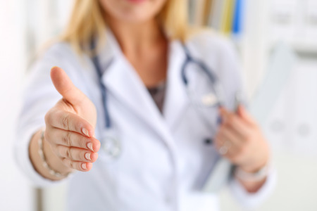 Female medicine doctor offering hand to shake in office closeup. Greeting and welcoming friend, introduction or thanks gesture. Tests advertisement concept. Physician ready to examine patientの写真素材