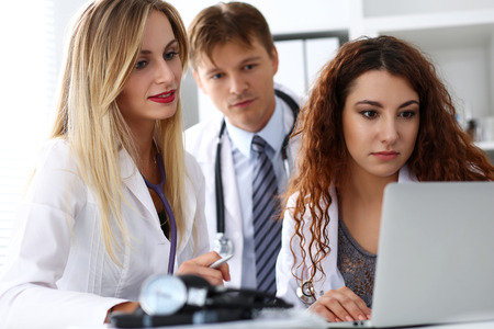 Group of doctors using laptop pc sitting in office. General practitioner portrait, telemedicine, therapeutist professional conversation, modern communication, remote cure, expert assistance conceptの写真素材