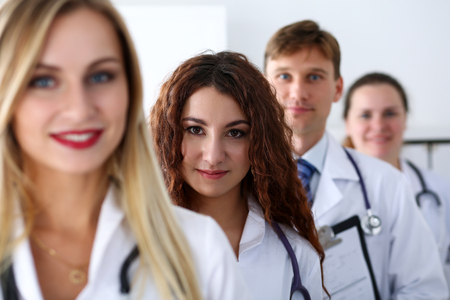 Group of medics proudly posing in row and looking in camera smiling. High level service, best treatment, 911, professional, healthy lifestyle, therapeutist consultation, physical, emergency conceptの写真素材