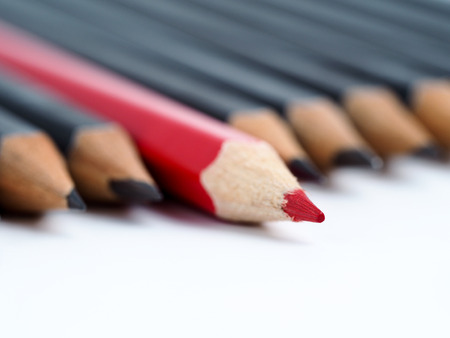 Red pencil standing out from crowd of plenty identical black fellows on white background. Leadership, uniqueness, independence, initiative, strategy, dissent, think different, business success conceptの写真素材
