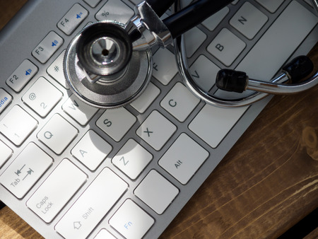 Stethoscope head lying on silver keyboard closeup. Physical, disease prevention, examine patient, 911, instrument shop, healthy lifestyle, modern medicine and high tech equipment conceptの写真素材