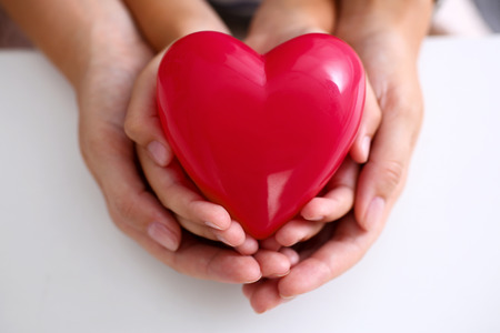 Woman and kid hold red toy heart in arms closeup. Female give birth to life, palm hug, diagnosis aid, healthy pregnancy, feel peace, donation service, souls together, abortion conceptの写真素材