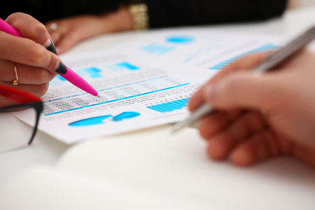 Female arm holding pink pen point in financial graphの写真素材