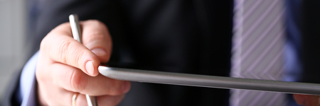 Businessman arm in suit and tie use silver pen and pad pc closeup. Stock market statistic student...
