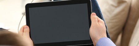 Male arms with pc pad wired to headphones at home closeup. Stock market trade and investment...