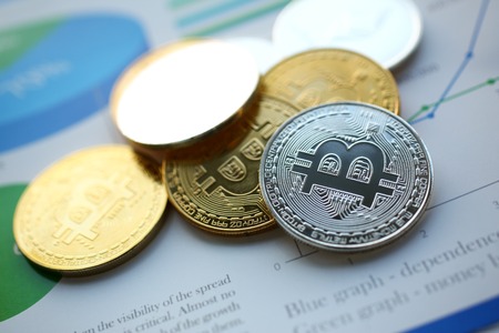 Set of bitcoin sign coins lying at stats graph paper closeup as idea of modern broker tool for...