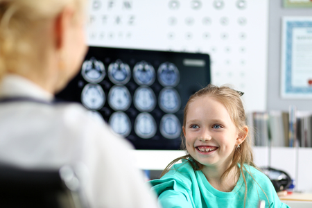 Smiling cute little girl talking to female doctor at her office portraitの写真素材