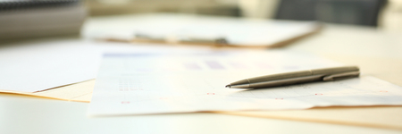 Letterbox of silver pen lie down at financial statistic document at empty working table closeupの写真素材