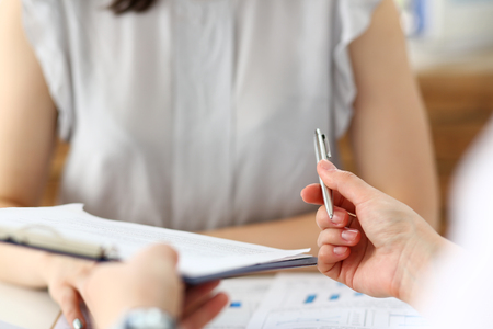 Male hand holding silver pen offering some papers for approval terms of cooperation pact closeupの写真素材