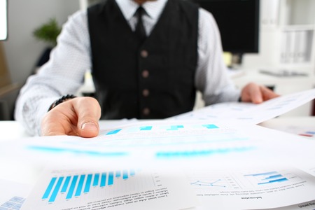 Male hands holding financial statistics documents searching for new opportunities in future closeup