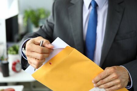Clerk in suit and tie at workplace packing envelope unpacking envelope with important documentation...