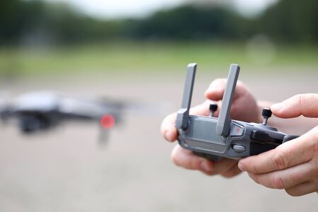 Modern video recording drone controlled with male hands holding remote controller closeupの写真素材