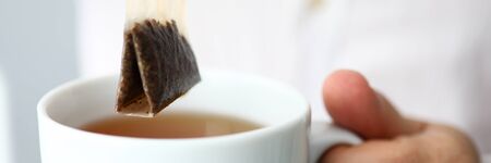 Letterbox view of man in white shirt stirring traditional healthy ceylon tea in cup close-upの写真素材
