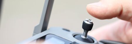 Letterbox view of male hand holding modern flying drone remote navigating it with stick macro