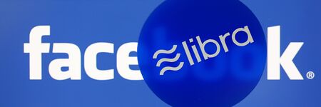 Minsk, Belarus, - June 09, 2019: Blue chip with libra sign lying on smartphone display with facebook...