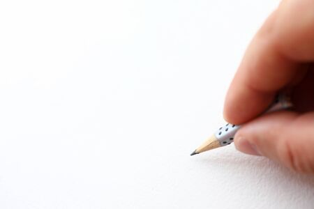 Male hand holding simple pencil stump ready to draw something on white paper macro