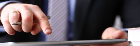 Letterbox view of male arm in suit and tie use silver pen and tablet pc close-up. Stock market statistic student read news via web or modern electronic bank assistance technology conceptの写真素材