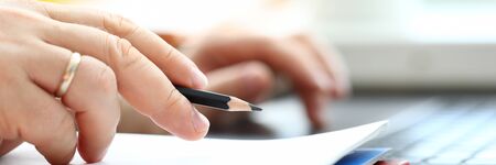 Letterbox view of man holding in arm regular lead pencil while typing something at laptop pc closeup