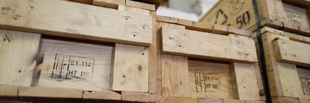 Letterbox view of stack of old wooden packaging boxes standing in column order close-up. Fragile...