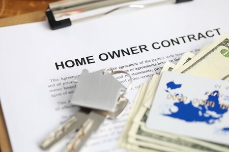 Close-up of important home owner contract and keys of new house for clients. Credit card and cash lying on table. Rental agreement and investment conceptの写真素材