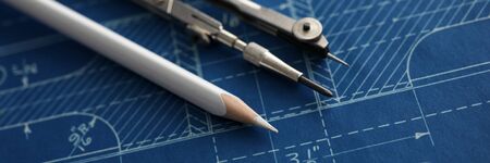 Letterbox view of drawing tools lying over blueprint paper close-up